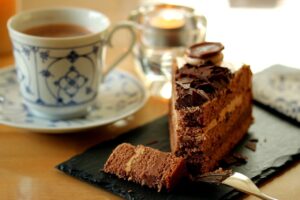 A slice of chocolate cake with a fork beside a cup of coffee on a table.